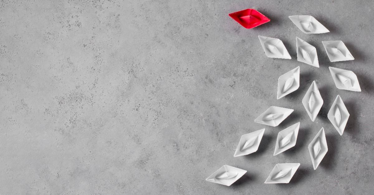 white paper boats led by a red paper boat