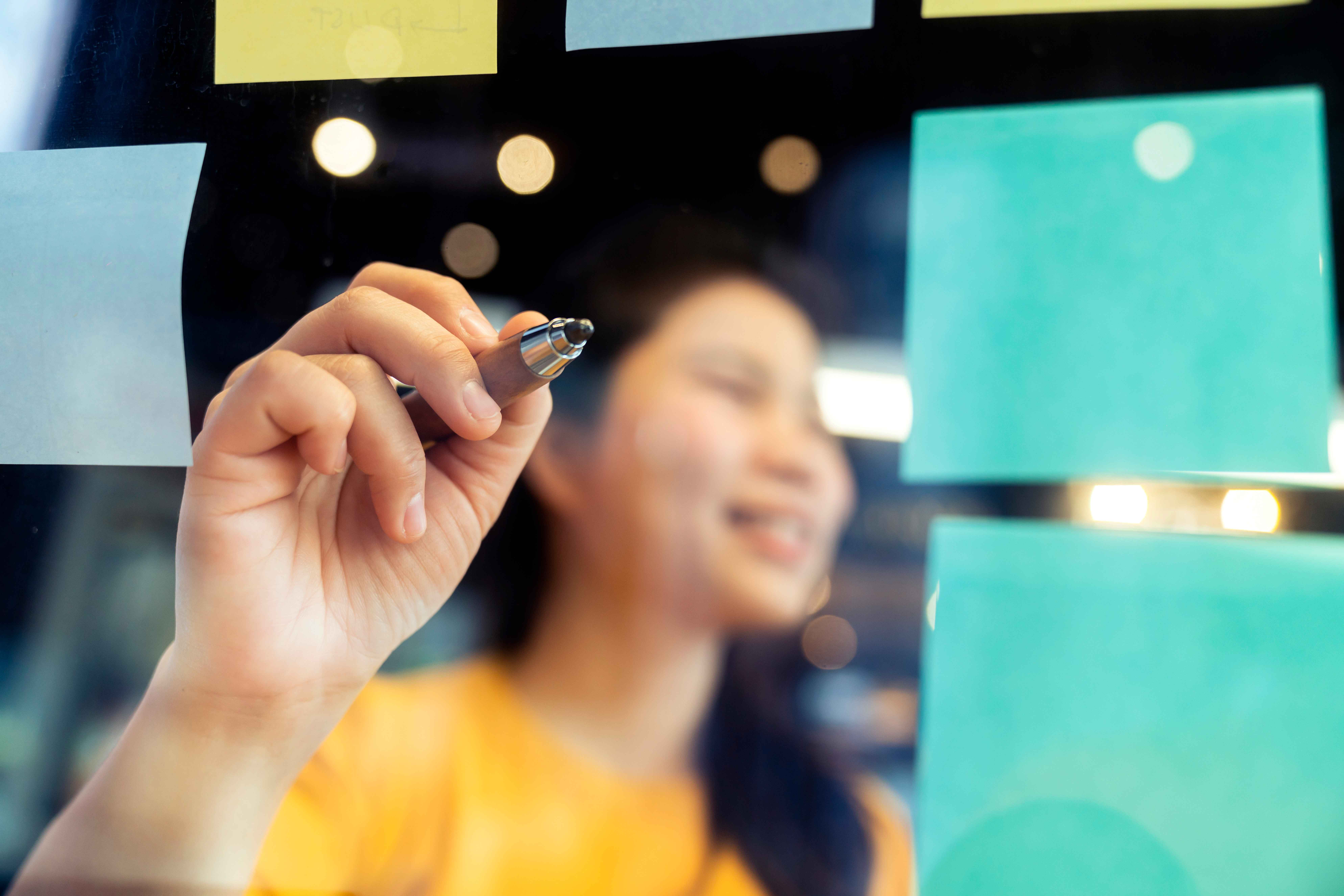 young asian woman writing on sticky notes