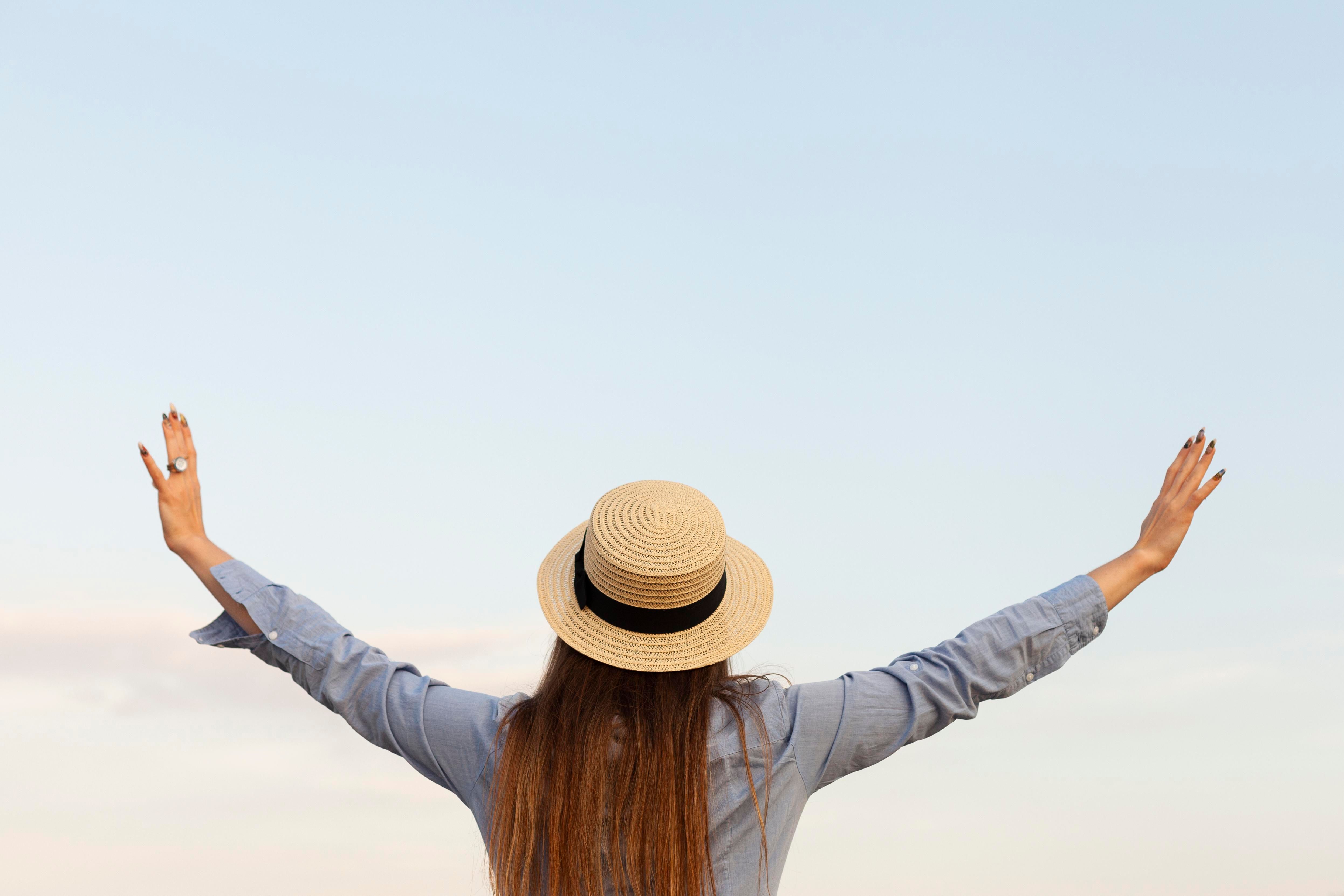 woman with a back view with open arms, posing outdoors, being free, living her life 