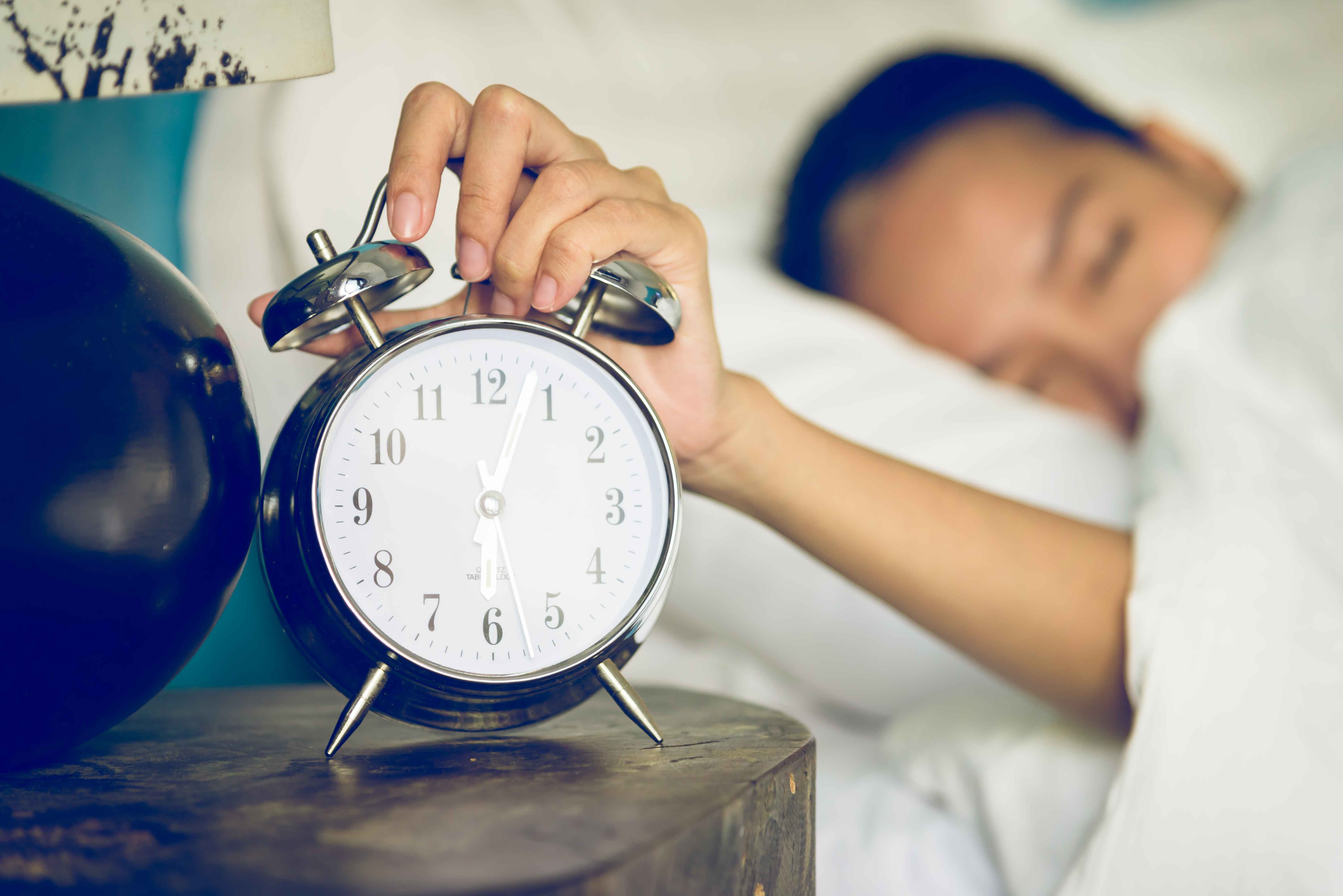 woman turning off her alarm clock in the morning