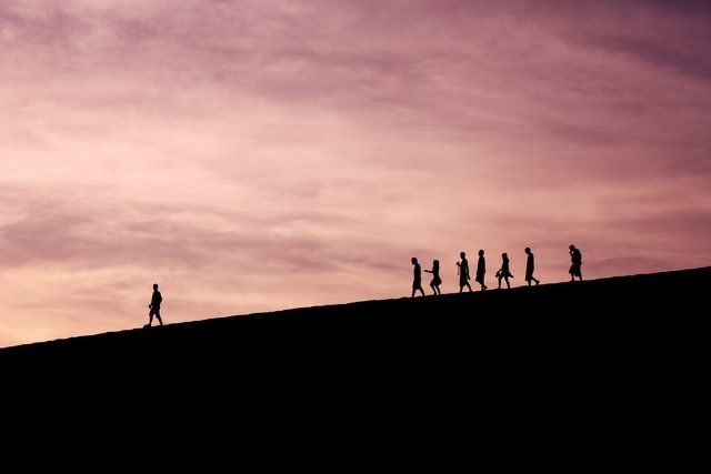 silhouette of people on hill with a leading man