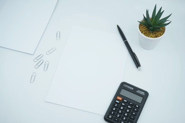 black calculator beside pen and paper