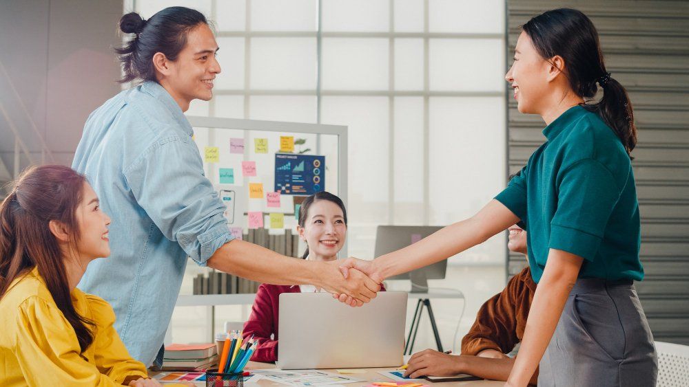 A man and woman are shaking hand that may indicate the good working relationship between them. 