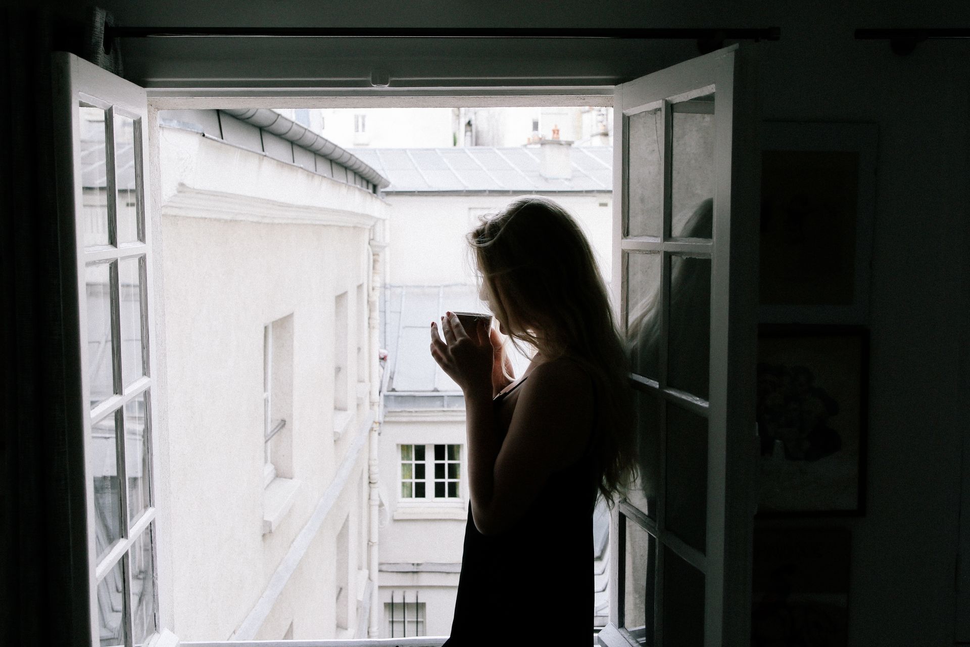 a woman sipping coffee by a window