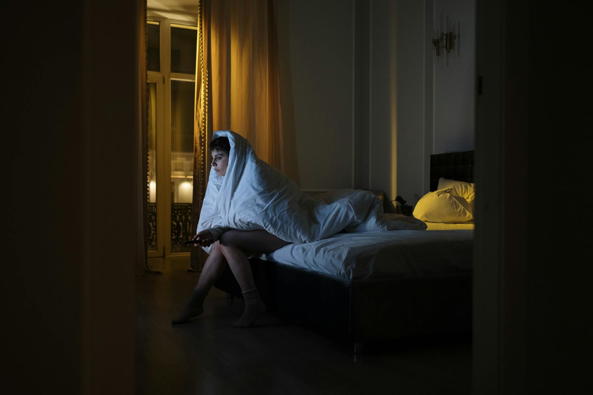 Woman wrapped in blanket watching TV