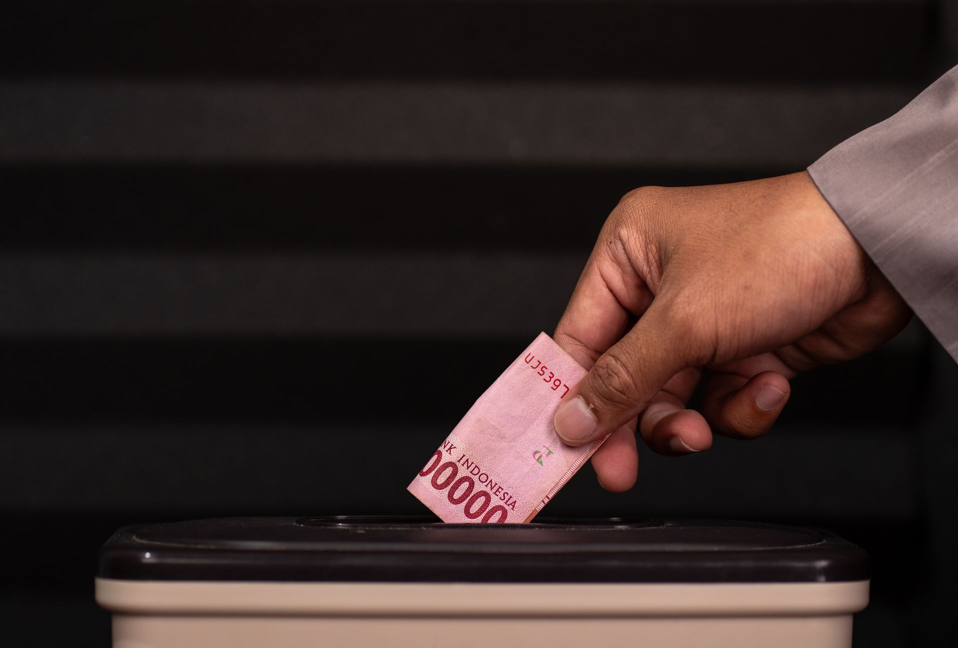 a hand placing money into a box