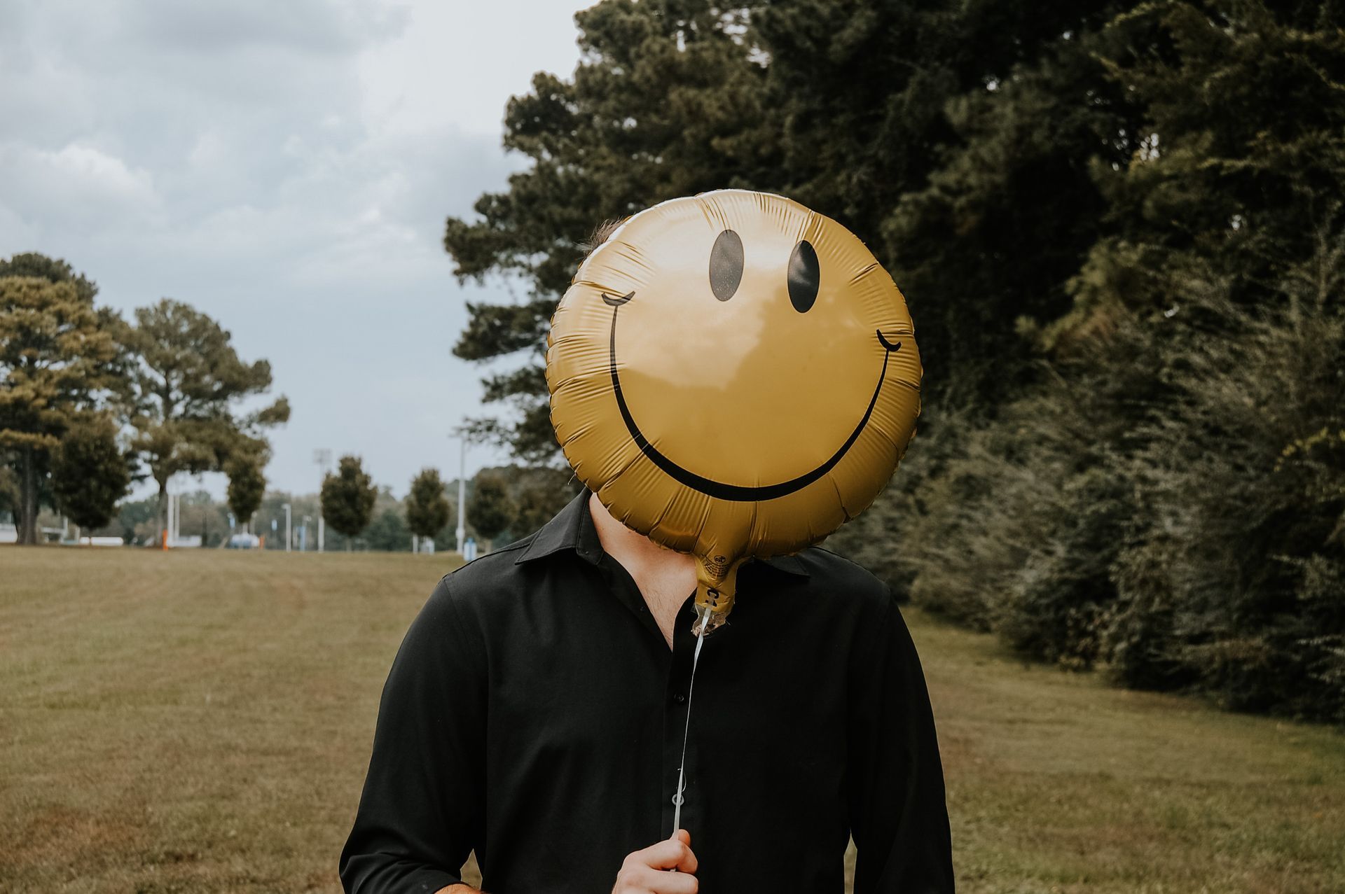 holds a smiley face balloon