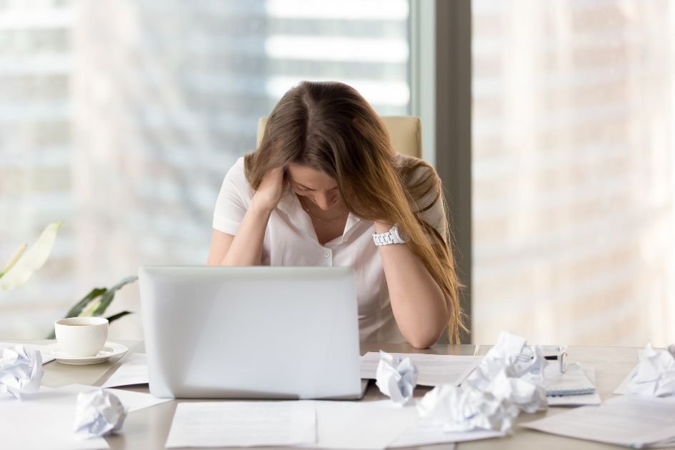 women stressed at work with crumpled paper on the table